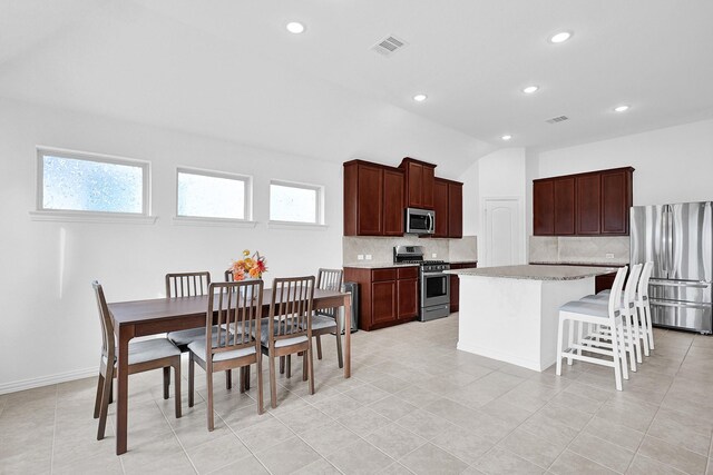 kitchen featuring a kitchen breakfast bar, tasteful backsplash, visible vents, and stainless steel appliances