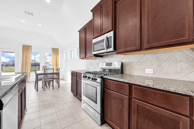 kitchen featuring light tile patterned floors, light stone counters, visible vents, appliances with stainless steel finishes, and tasteful backsplash