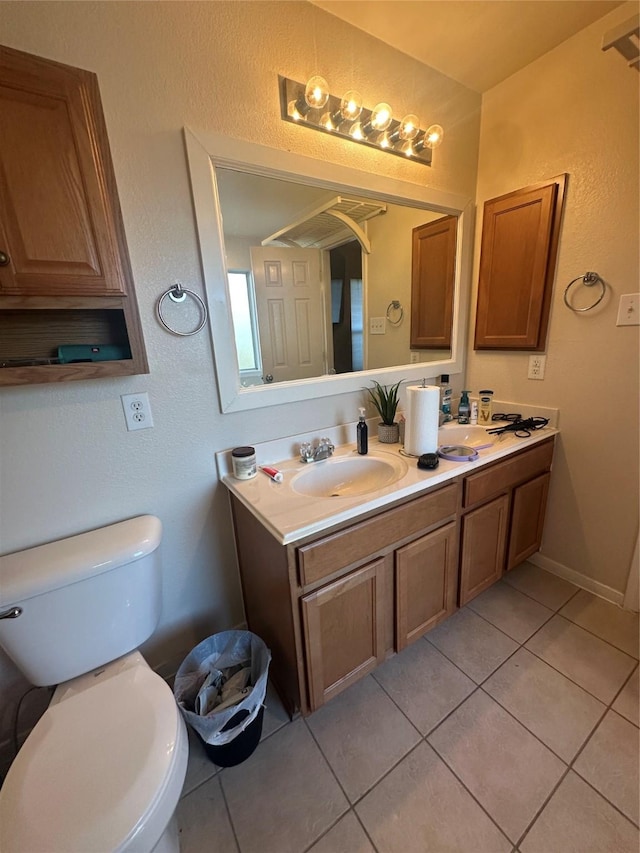 bathroom featuring double vanity, baseboards, toilet, tile patterned flooring, and a sink