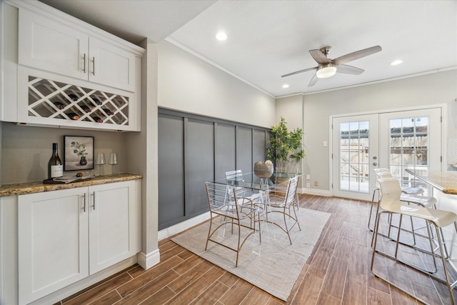 dining room featuring a dry bar, ceiling fan, wood tiled floor, crown molding, and french doors