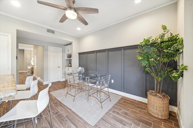 dining space with a ceiling fan, wood finish floors, visible vents, and ornamental molding