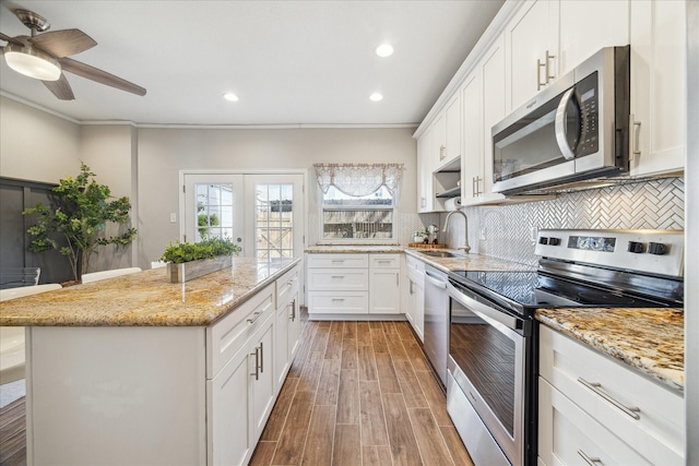 kitchen featuring stainless steel appliances, a kitchen island, a sink, and tasteful backsplash