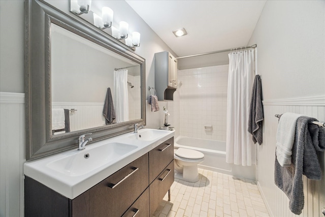 bathroom with double vanity, wainscoting, a sink, and shower / bath combo with shower curtain