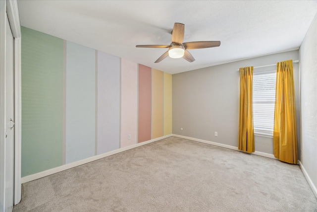 spare room featuring carpet flooring, ceiling fan, and baseboards