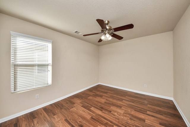 empty room featuring a ceiling fan, baseboards, visible vents, and dark wood-style flooring