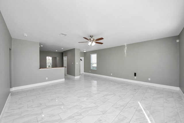 spare room featuring a ceiling fan, marble finish floor, visible vents, and baseboards