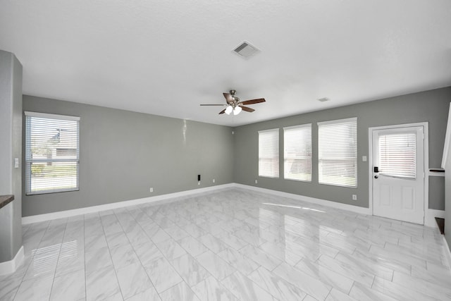 unfurnished room with baseboards, visible vents, and a ceiling fan