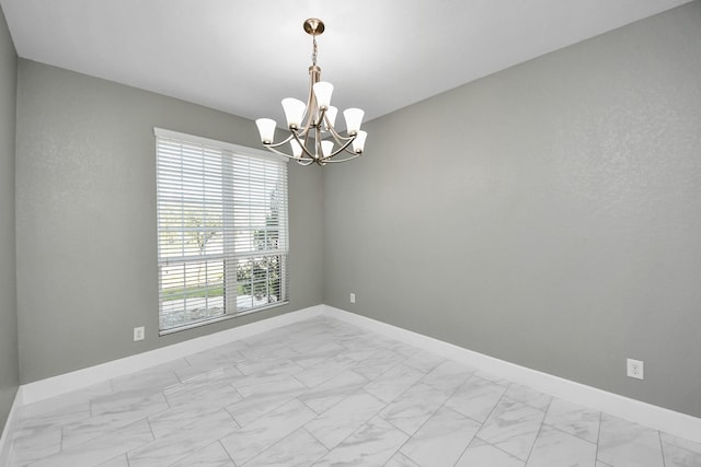 empty room featuring marble finish floor, an inviting chandelier, and baseboards