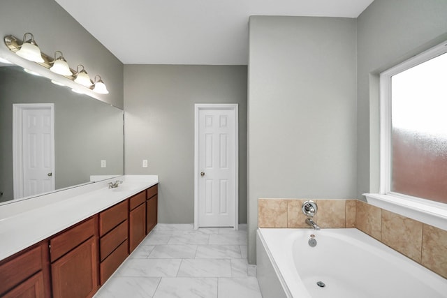 full bathroom featuring marble finish floor, a garden tub, and vanity