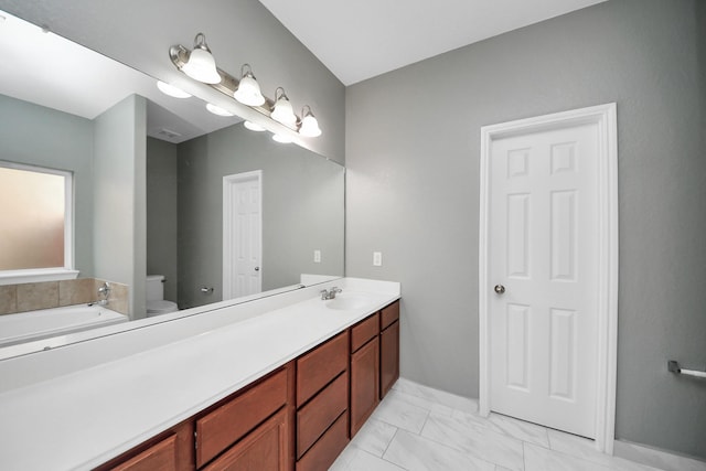 bathroom with a garden tub, marble finish floor, vanity, and toilet