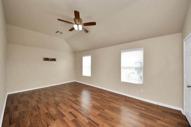 unfurnished room featuring lofted ceiling, dark wood-type flooring, a ceiling fan, visible vents, and baseboards