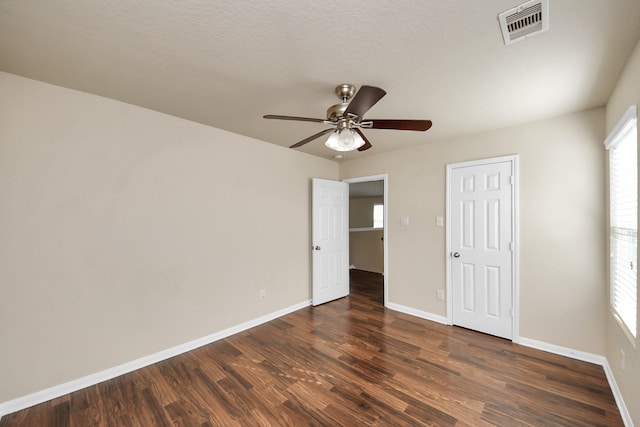 unfurnished bedroom with baseboards, visible vents, dark wood finished floors, and a ceiling fan