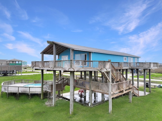 back of property with a deck, a yard, stairway, and a fenced in pool