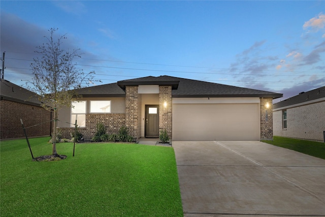 prairie-style home with a garage, driveway, brick siding, roof with shingles, and a front yard