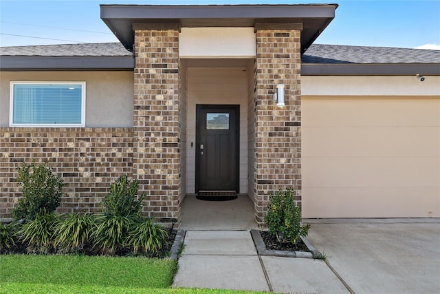 property entrance featuring an attached garage, a shingled roof, and brick siding