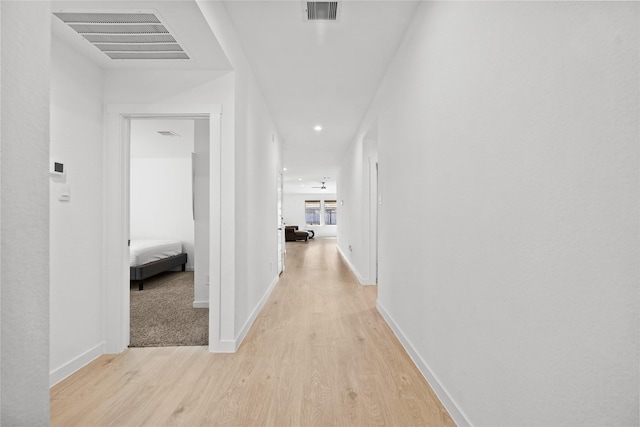 corridor featuring visible vents, light wood-style flooring, and baseboards