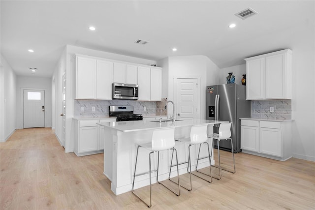 kitchen featuring a sink, stainless steel appliances, a center island with sink, and visible vents