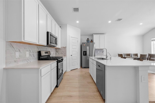 kitchen featuring a center island with sink, visible vents, stainless steel appliances, and a sink