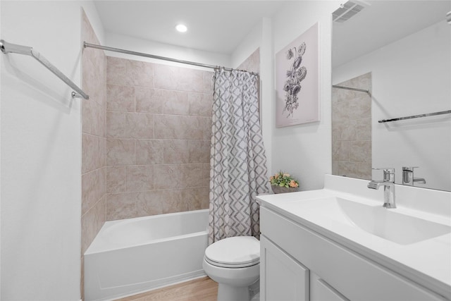 bathroom featuring toilet, wood finished floors, vanity, visible vents, and shower / bath combo with shower curtain