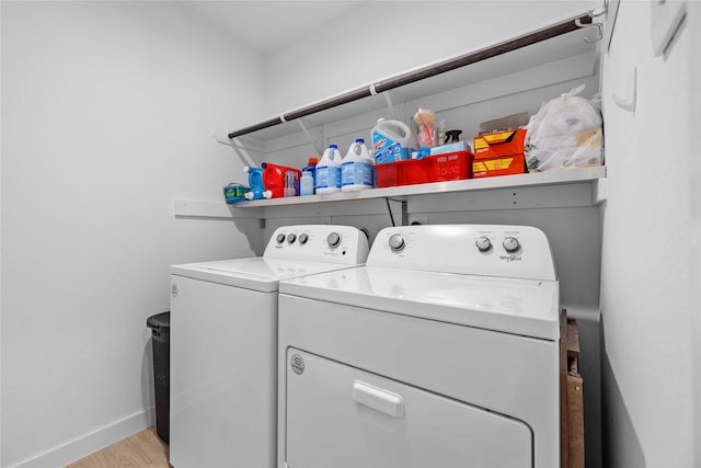 clothes washing area featuring light wood-type flooring, laundry area, baseboards, and washer and dryer