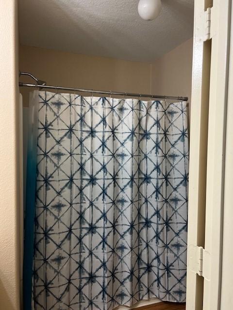 bathroom featuring a shower with curtain and a textured ceiling