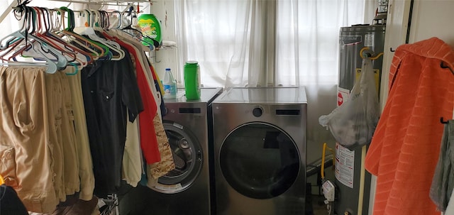 washroom featuring water heater, laundry area, and washer and clothes dryer