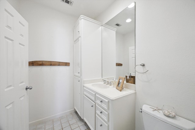 half bath with visible vents, vanity, toilet, and tile patterned floors