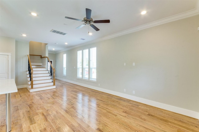 unfurnished living room with light wood-style flooring, visible vents, baseboards, ornamental molding, and stairway