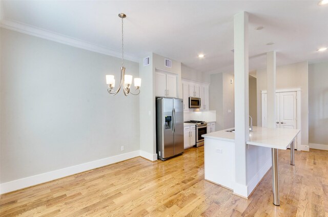 kitchen featuring light wood finished floors, light countertops, appliances with stainless steel finishes, and baseboards