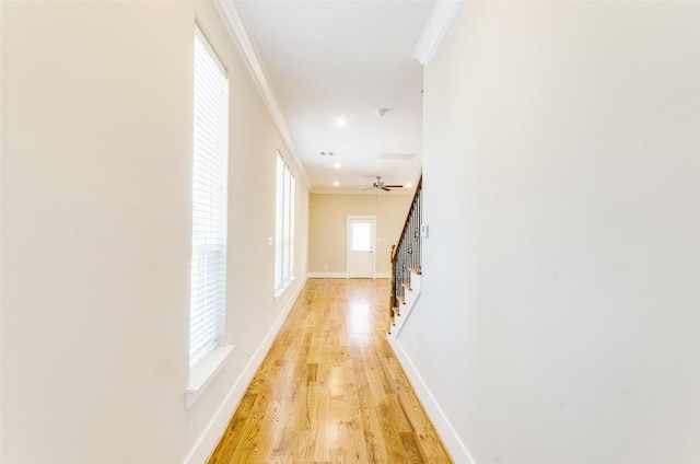 hall with light wood finished floors, baseboards, stairs, and ornamental molding