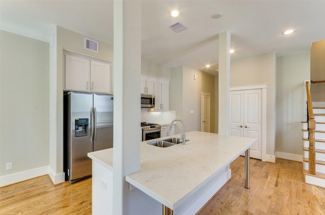 kitchen featuring stainless steel appliances, light wood-type flooring, a sink, and visible vents