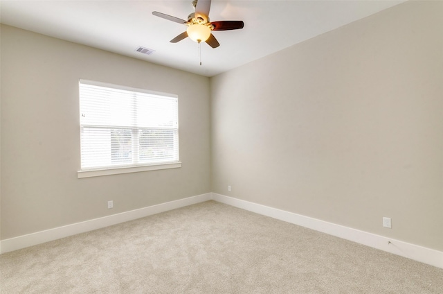 empty room featuring a ceiling fan, visible vents, light carpet, and baseboards