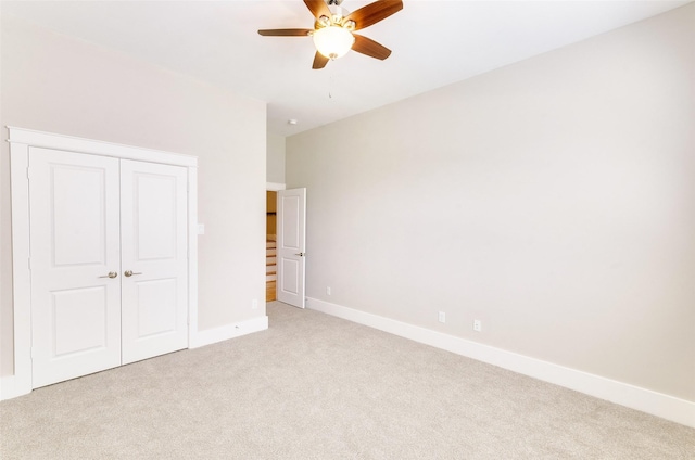 unfurnished bedroom with baseboards, ceiling fan, a closet, and light colored carpet