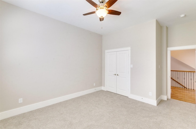 unfurnished bedroom with light carpet, a closet, a ceiling fan, and baseboards