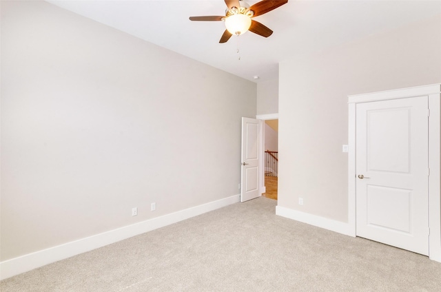 unfurnished bedroom with a ceiling fan, light colored carpet, and baseboards