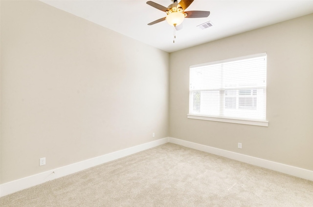 empty room featuring baseboards, visible vents, ceiling fan, and light colored carpet