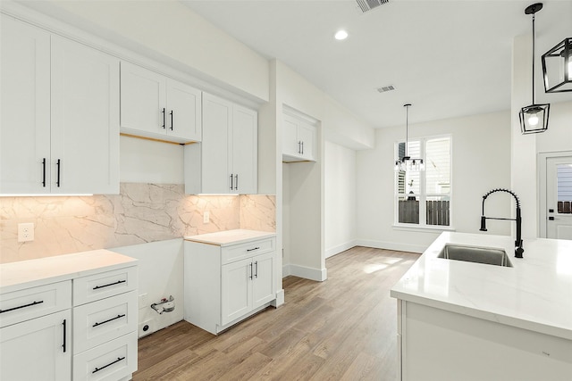 kitchen featuring a sink, backsplash, light wood-style floors, white cabinetry, and recessed lighting