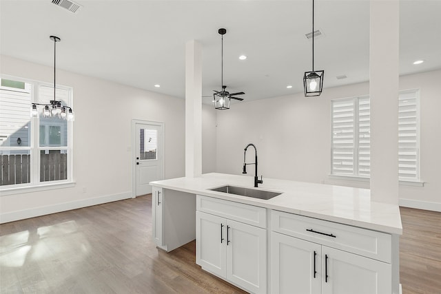 kitchen featuring a sink, white cabinetry, light wood finished floors, ceiling fan, and decorative light fixtures