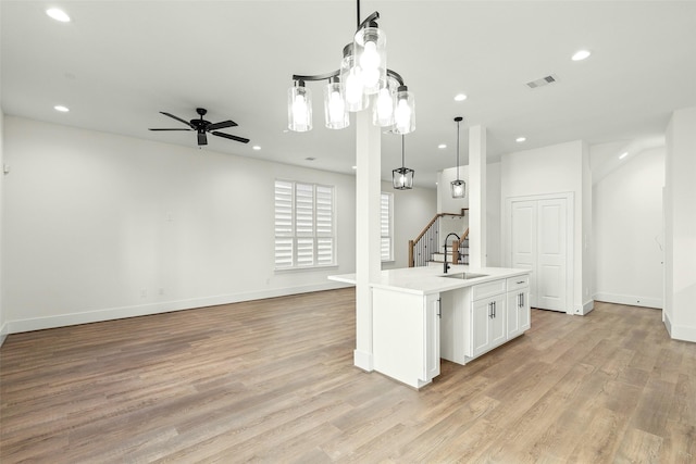 kitchen featuring open floor plan, a sink, recessed lighting, light wood finished floors, and baseboards