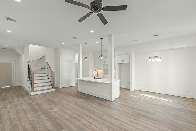 unfurnished living room featuring light wood-type flooring, ceiling fan, recessed lighting, a sink, and baseboards