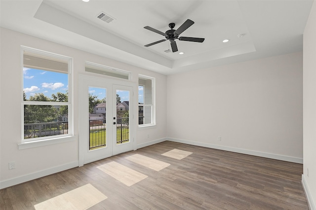 spare room featuring a raised ceiling, french doors, baseboards, wood finished floors, and a ceiling fan