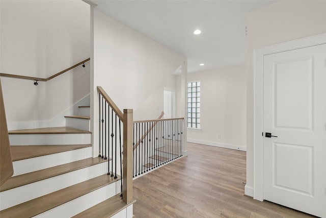 stairs with wood finished floors, recessed lighting, and baseboards
