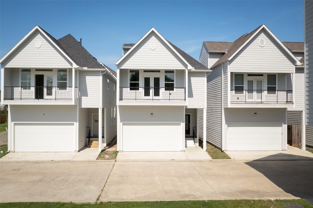 coastal inspired home with a balcony, an attached garage, and french doors