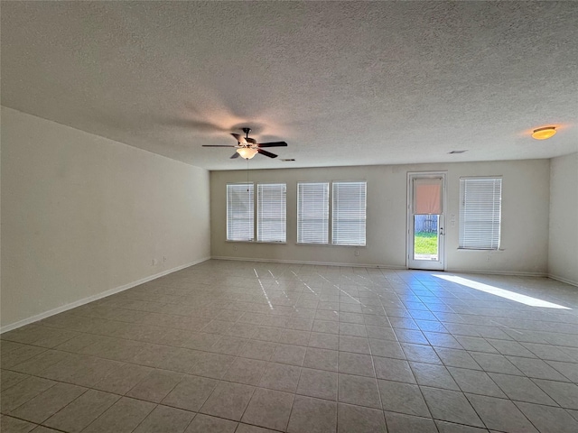 unfurnished room with a textured ceiling, tile patterned floors, a ceiling fan, and baseboards