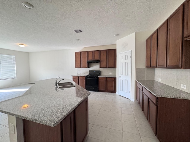 kitchen featuring visible vents, black range with gas stovetop, decorative backsplash, and a sink