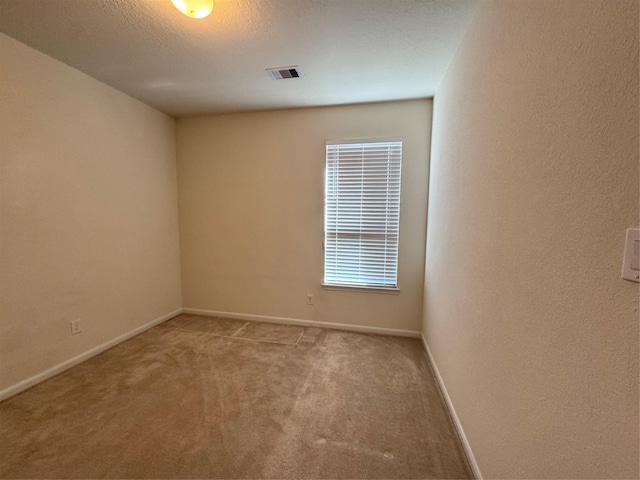 unfurnished room featuring a textured ceiling, carpet floors, visible vents, and baseboards