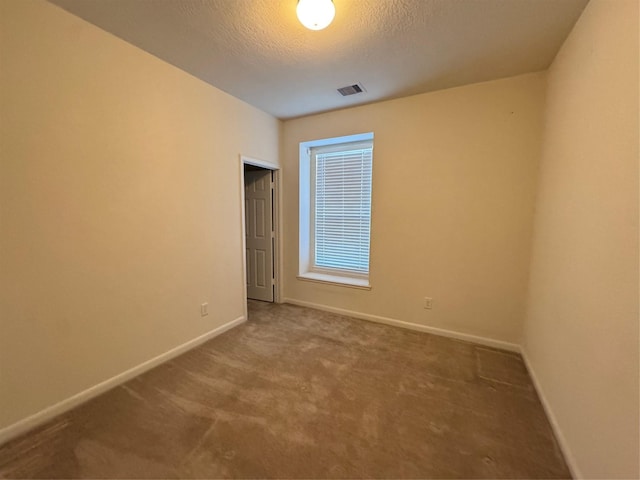 carpeted empty room featuring baseboards, visible vents, and a textured ceiling