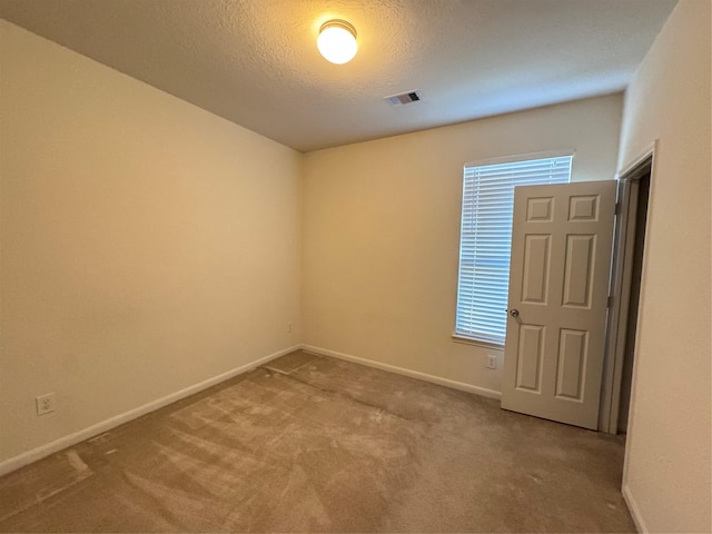 unfurnished room featuring visible vents, carpet flooring, a textured ceiling, and baseboards