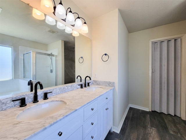 full bathroom featuring a stall shower, visible vents, a sink, and wood finished floors