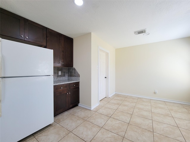 kitchen featuring visible vents, decorative backsplash, dark brown cabinets, and freestanding refrigerator